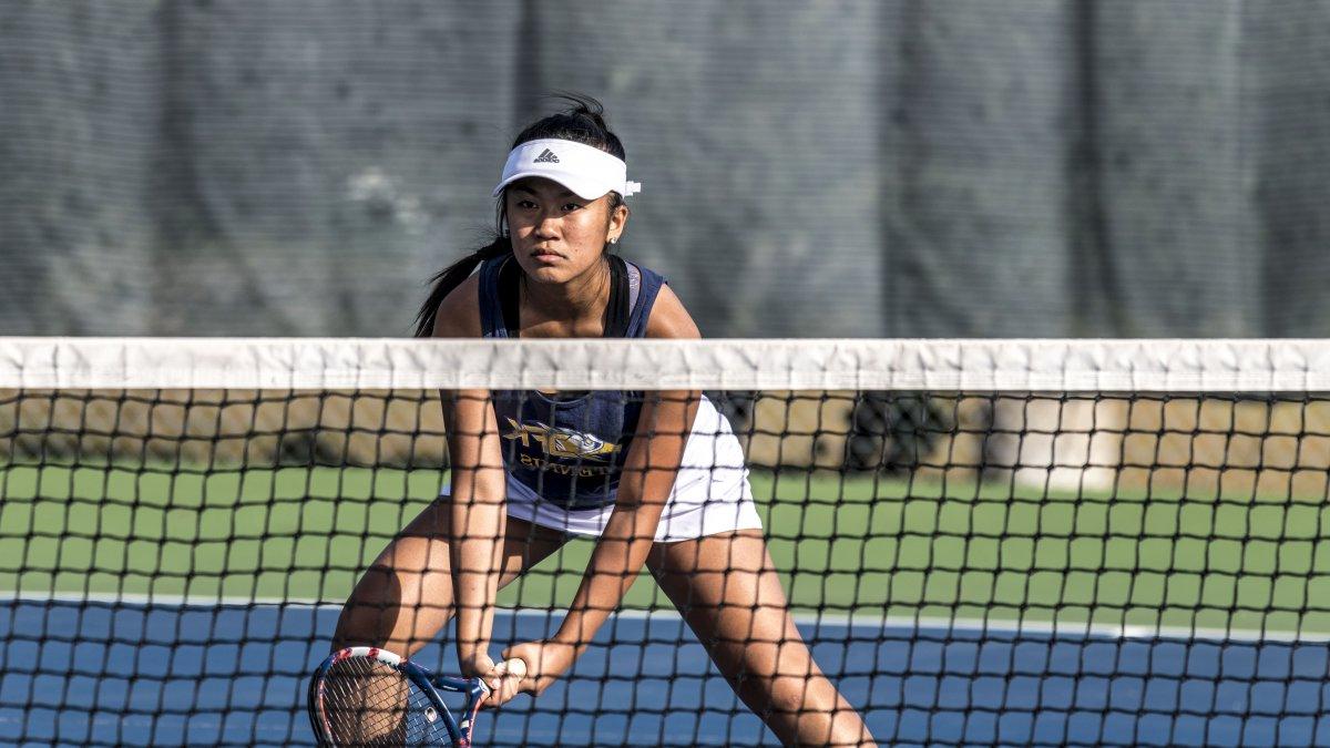 A Kennedy girls tennis player stands ready at the net