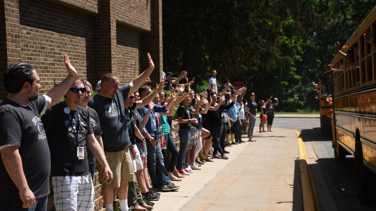 Staff members wave to departing buses