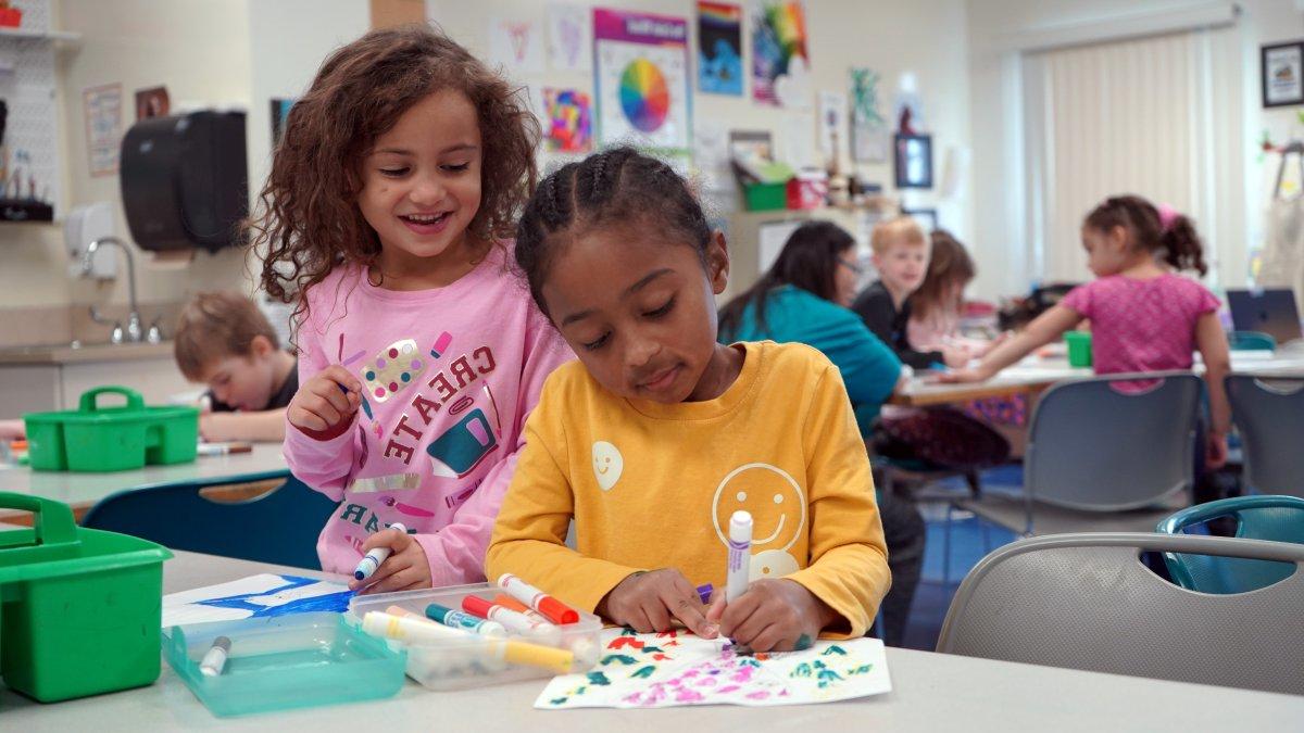 two students drawing with markers