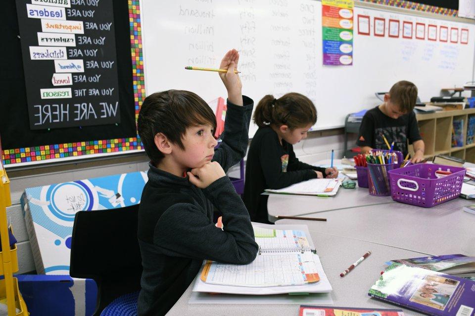 Boy raising his hand at his desk