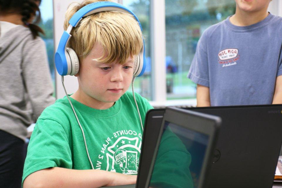 Student works on a laptop with headphones on